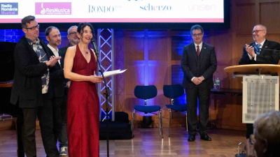 A woman with red robe speaks at an award ceremony.